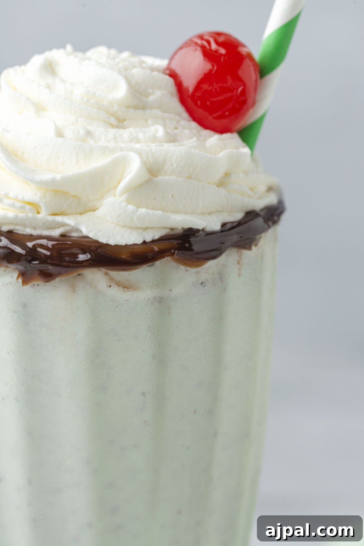 Cool Mint Swirl 9 A homemade shamrock shake, blended from mint ice cream, topped with whipped cream, and garnished with a cherry, presented in a tall glass with a chocolate-rimmed edge.