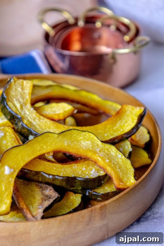 Beautifully roasted acorn squash slices, seasoned with a hint of salt, piled invitingly in a rustic wooden bowl.