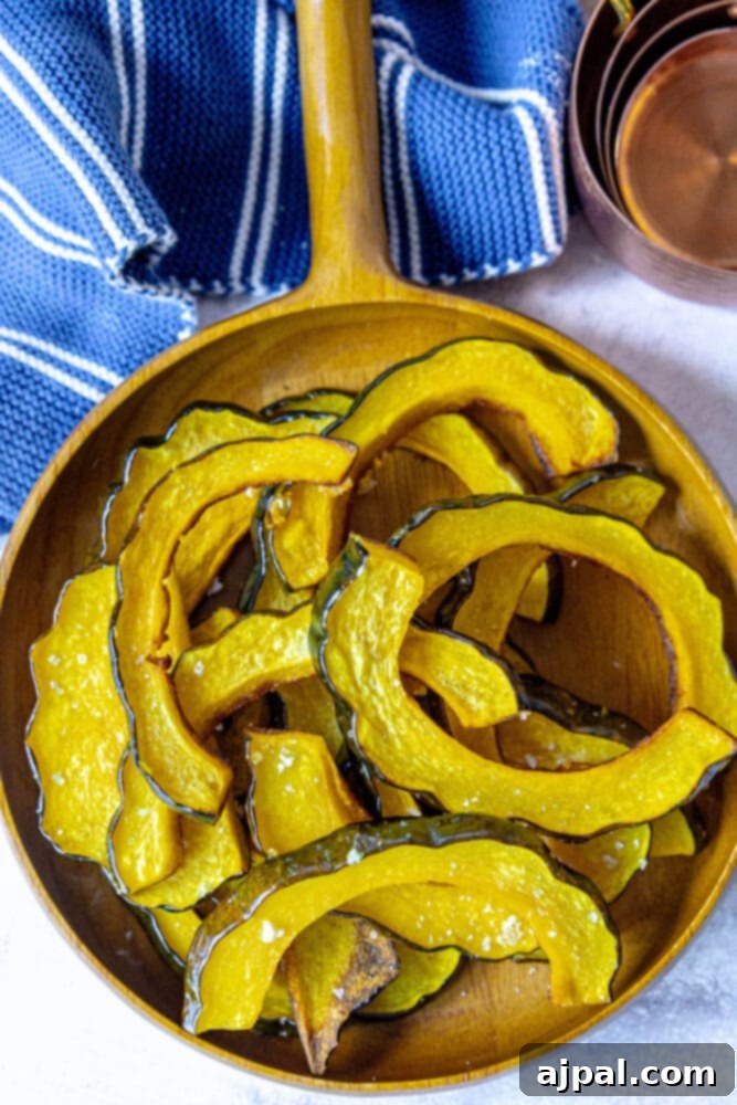 A close-up of tender, salted roasted acorn squash slices arranged on a soft blue towel, highlighting their golden-brown edges.