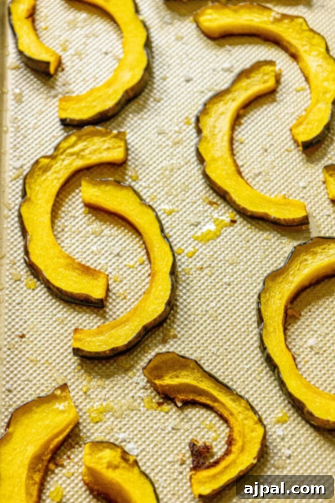 A freshly roasted batch of acorn squash slices, golden-brown and tender, arranged on a baking sheet, straight from the oven.