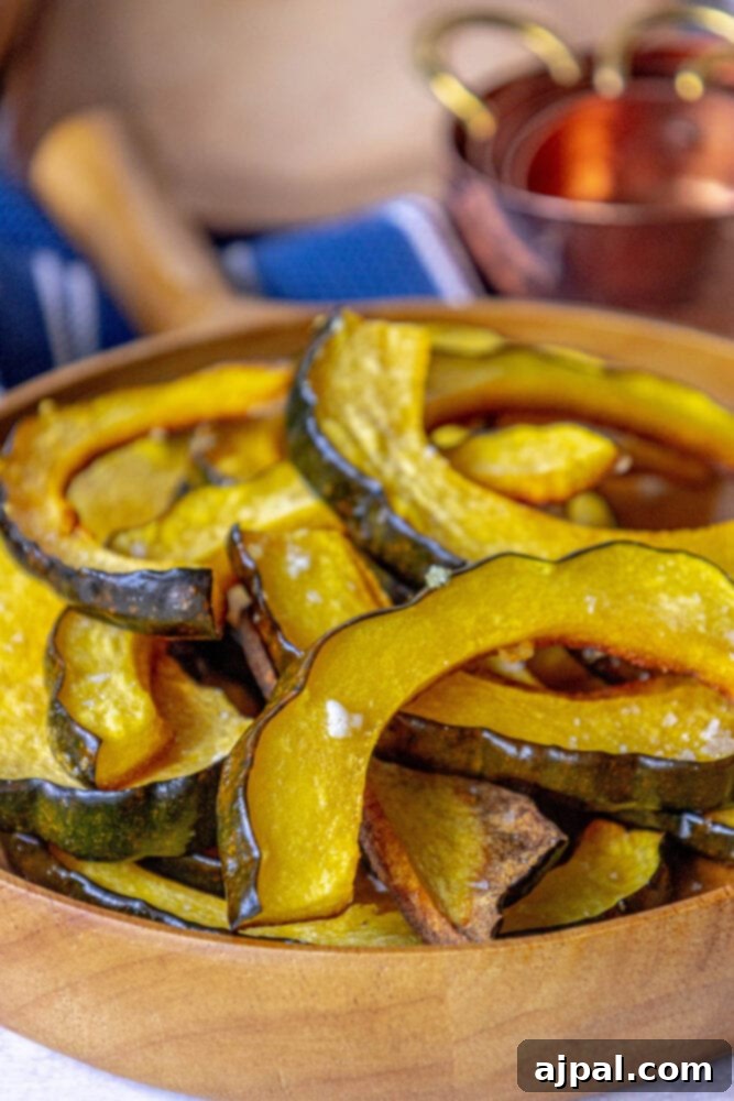 A generous serving of savory roasted acorn squash slices, perfectly seasoned and piled high in a classic wooden bowl, ready to be enjoyed.