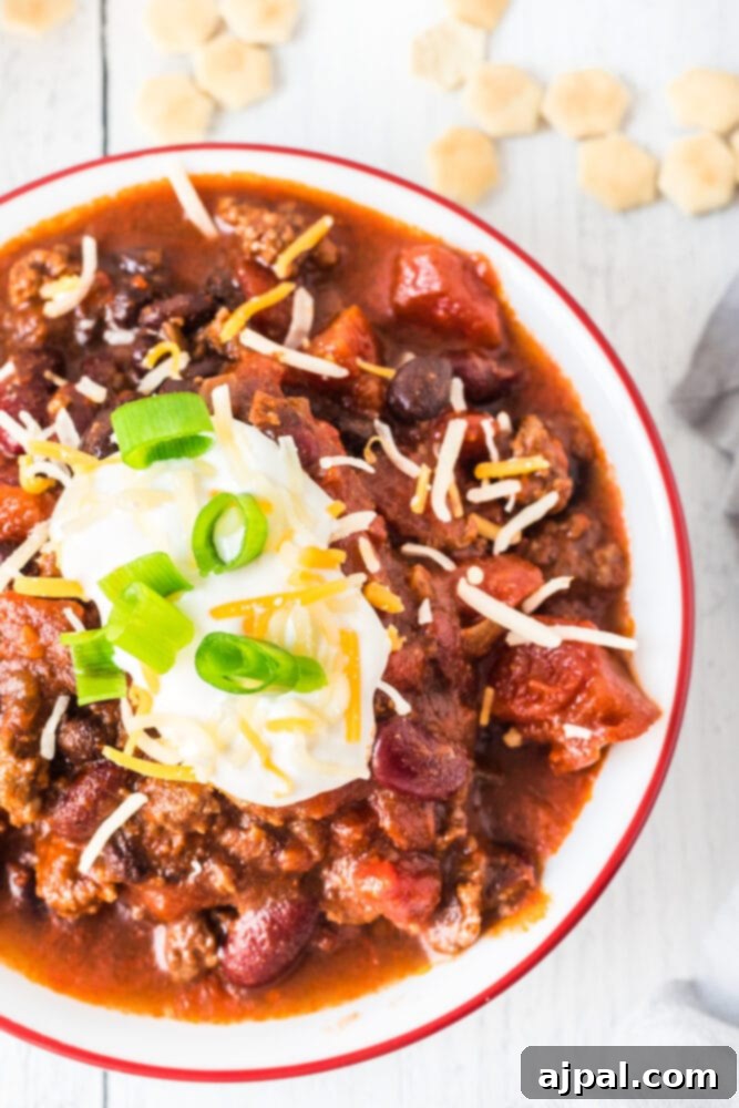picture of chili in a bowl with sour cream, green onions, and cheese on top