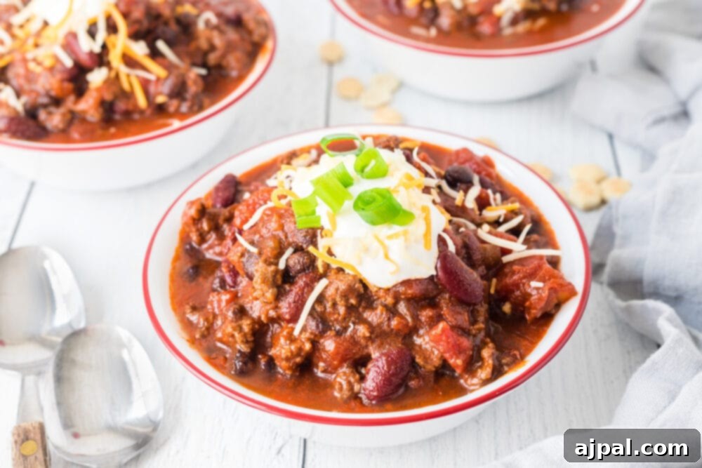 picture of chili in a bowl with sour cream, green onions, and cheese on top