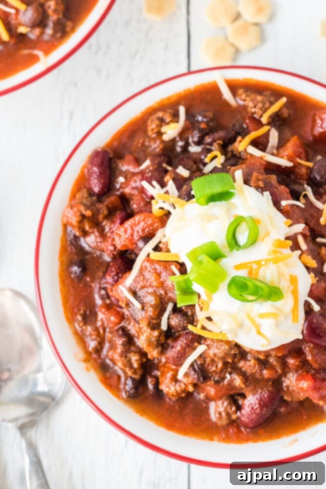 picture of chili in a bowl with sour cream, green onions, and cheese on top