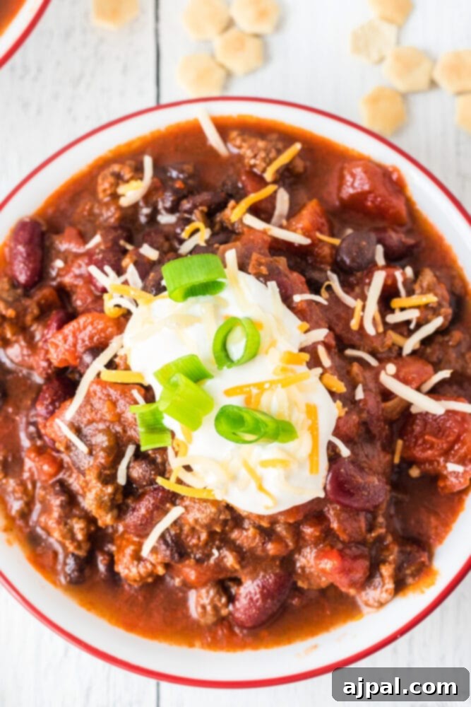 picture of chili in a bowl with sour cream, green onions, and cheese on top