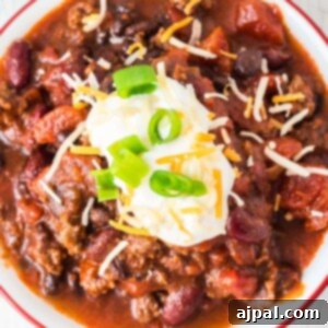 picture of chili in a bowl with sour cream, green onions, and cheese on top