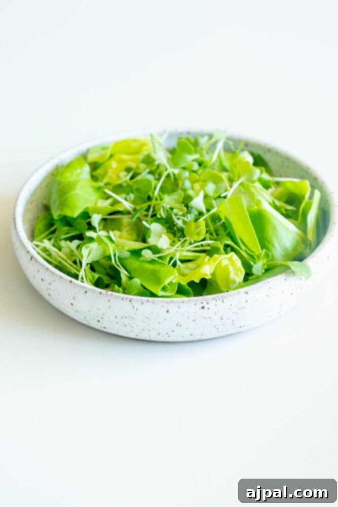 Crisp green butter lettuce leaves on a white plate, ready for salad assembly.