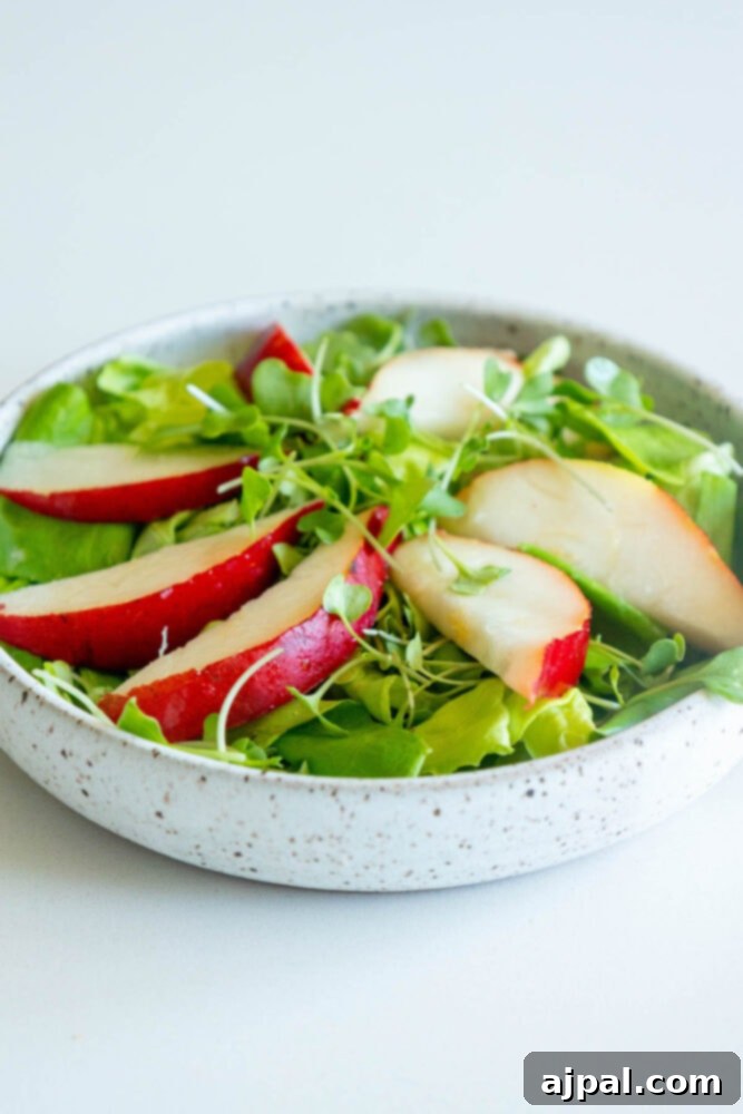 Fresh butter lettuce on a plate, layered with thin slices of ripe pear, awaiting the goat cheese.