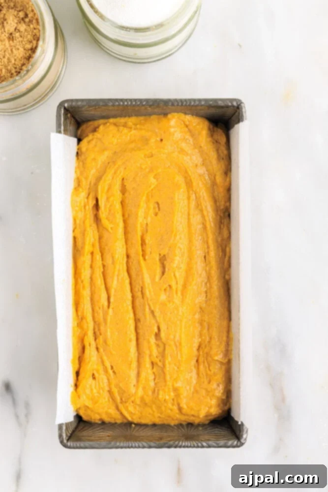 Moist Spiced Pumpkin Loaf 11 picture of pumpkin bread batter in a loaf pan lined with parchment paper