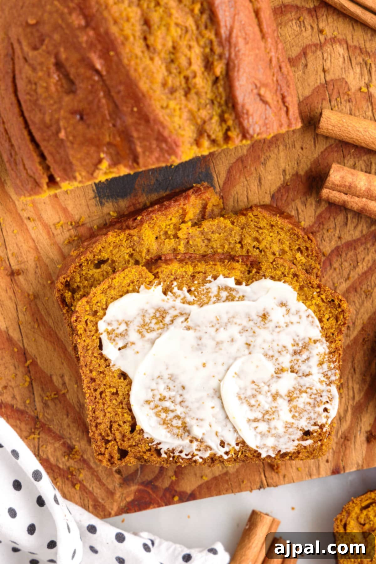 Moist Spiced Pumpkin Loaf 3 A deliciously baked pumpkin bread on a cutting board, garnished with cinnamon sticks.