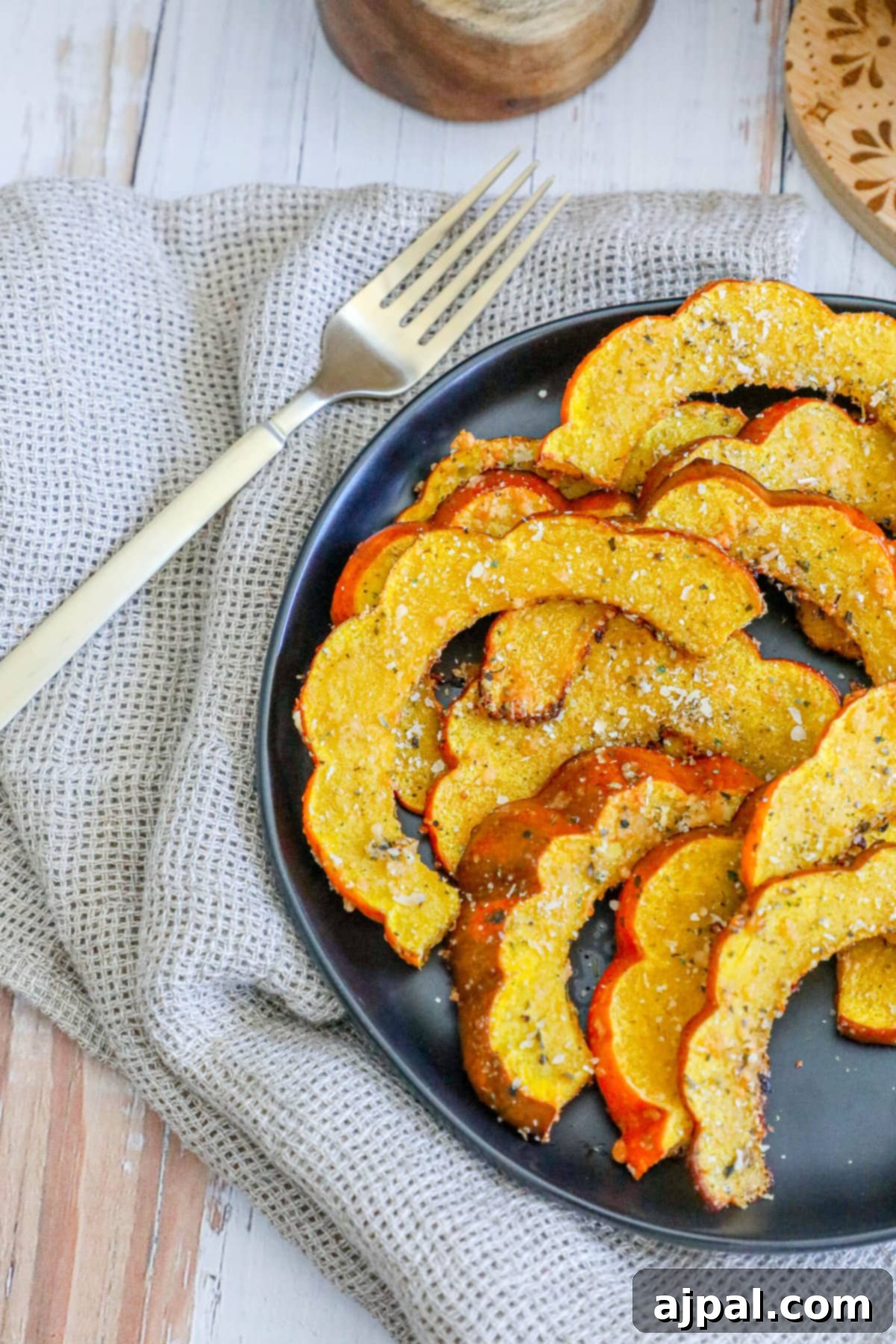 Picture of herbed acorn squash slices, beautifully arranged and ready to be served on a plate with a fork.