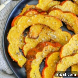 Picture of roasted acorn squash seasoned with herbs and spices on a black plate.