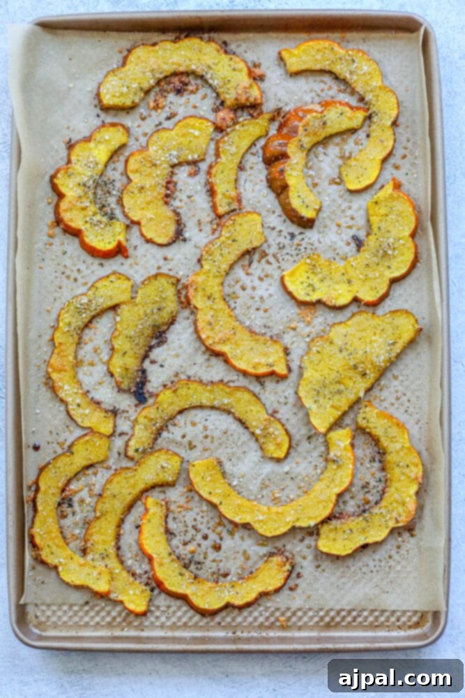 A baking sheet with herb roasted acorn squash slices, golden brown and crispy from the oven.