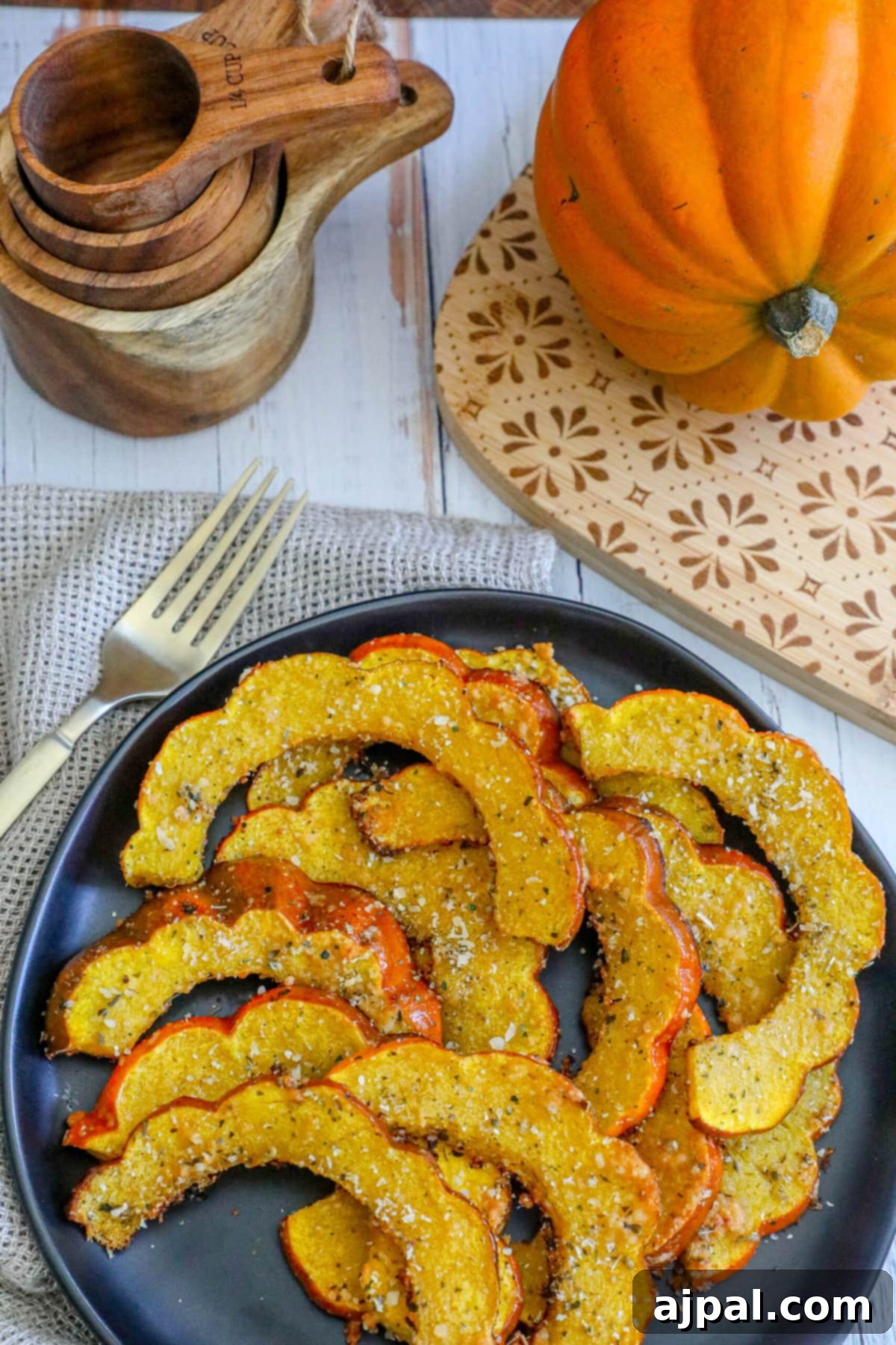 Picture of roasted acorn squash slices seasoned with herbs and spices on a black plate, ready to be enjoyed with a fork.