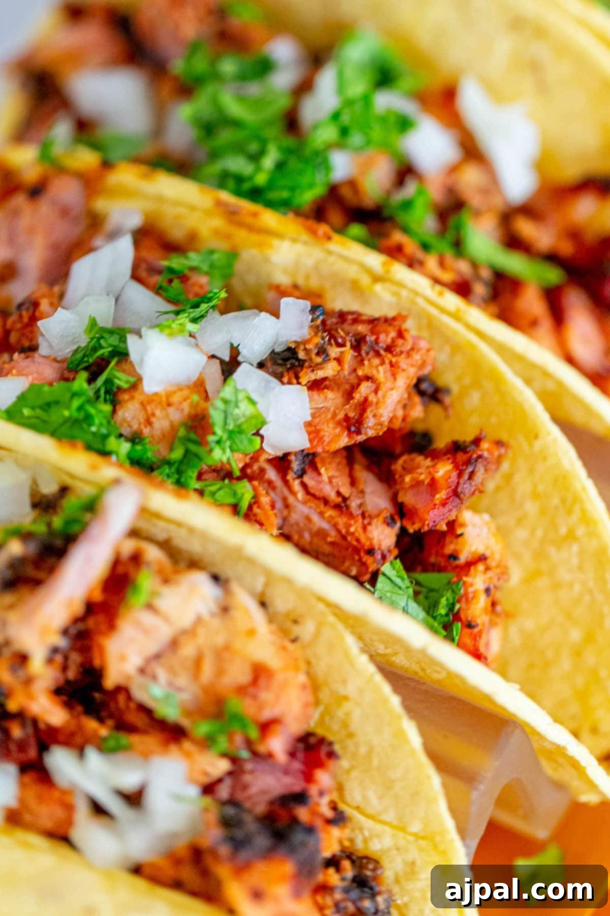 picture of chopped smoked al pastor in a taco topped with chopped cilantro and white onion