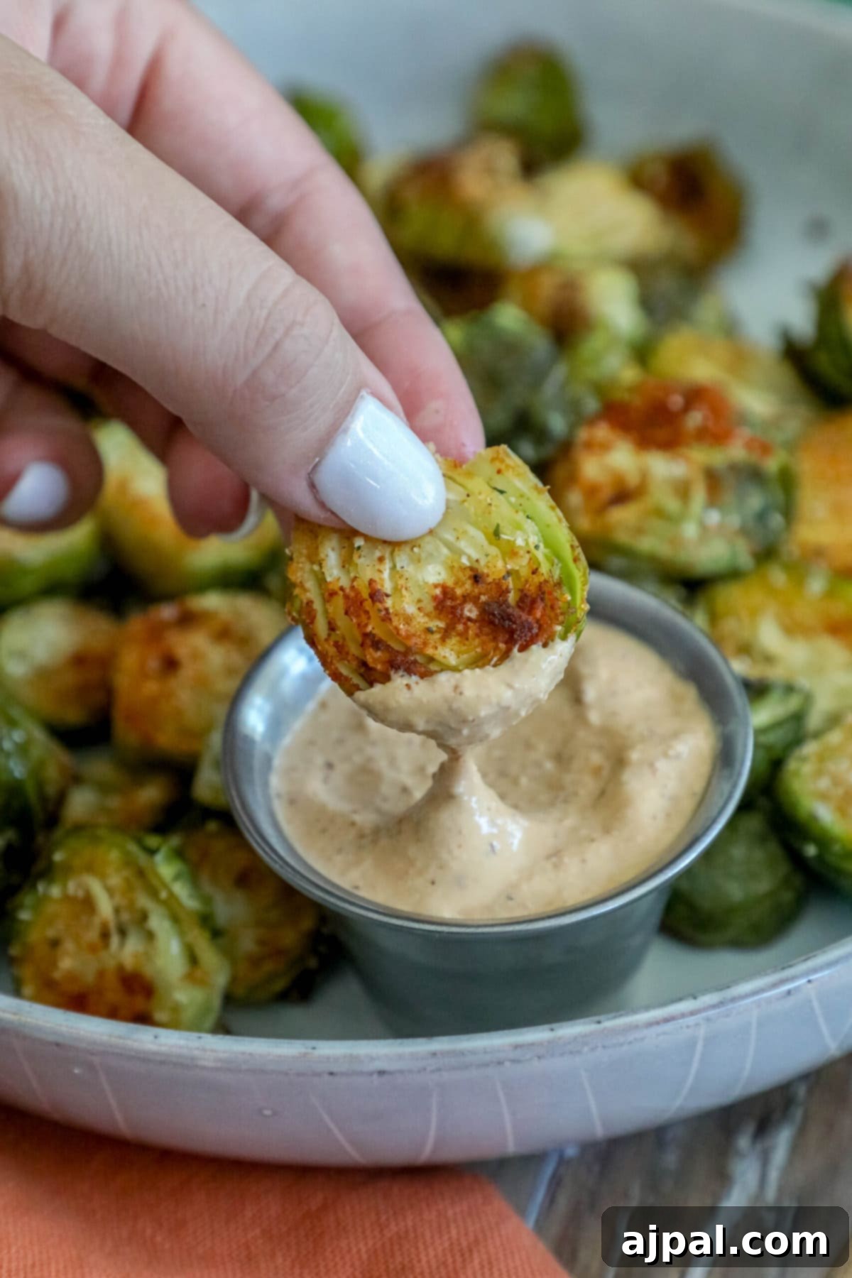 Crispy Garlic Roasted Brussels 3 A vibrant platter of garlic-roasted Brussels sprouts, perfectly caramelized and served with a creamy dipping sauce, ready to be enjoyed as a gourmet side dish.