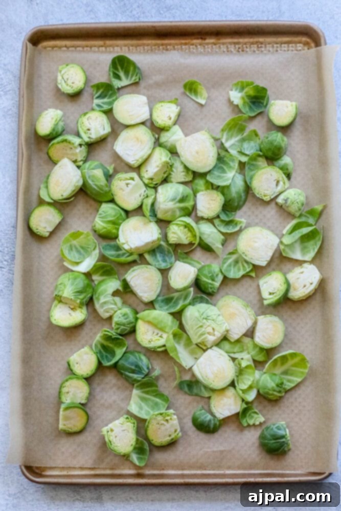 Crispy Garlic Roasted Brussels 6 Trimmed and halved Brussels sprouts neatly arranged on a baking sheet lined with parchment paper, prepped for roasting.