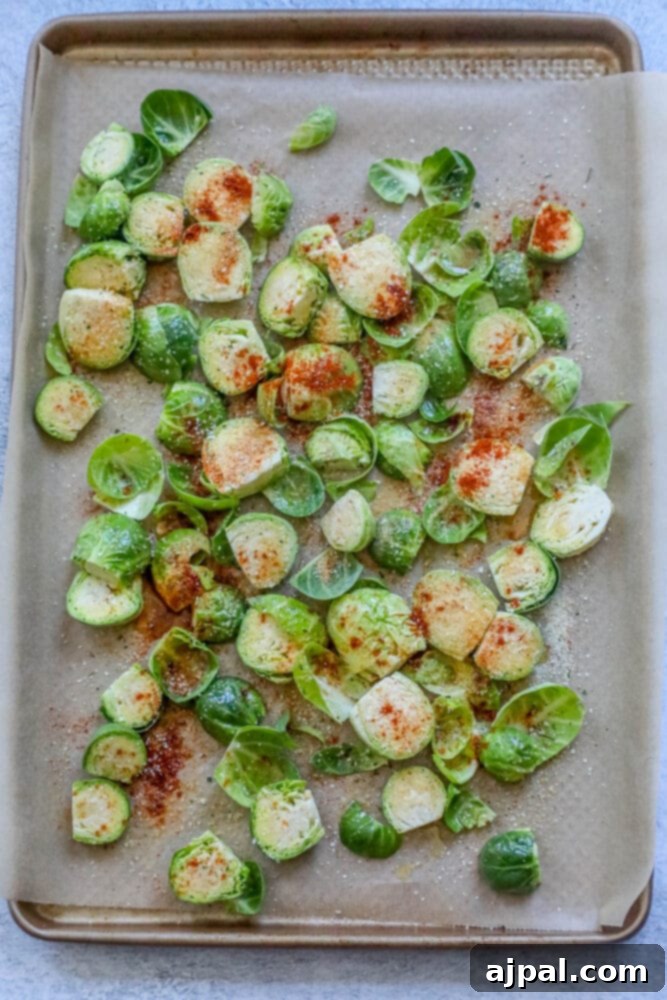 Crispy Garlic Roasted Brussels 7 Halved Brussels sprouts glistening with olive oil and seasoned with a generous blend of garlic powder, garlic salt, and paprika, spread on a parchment-lined baking sheet.