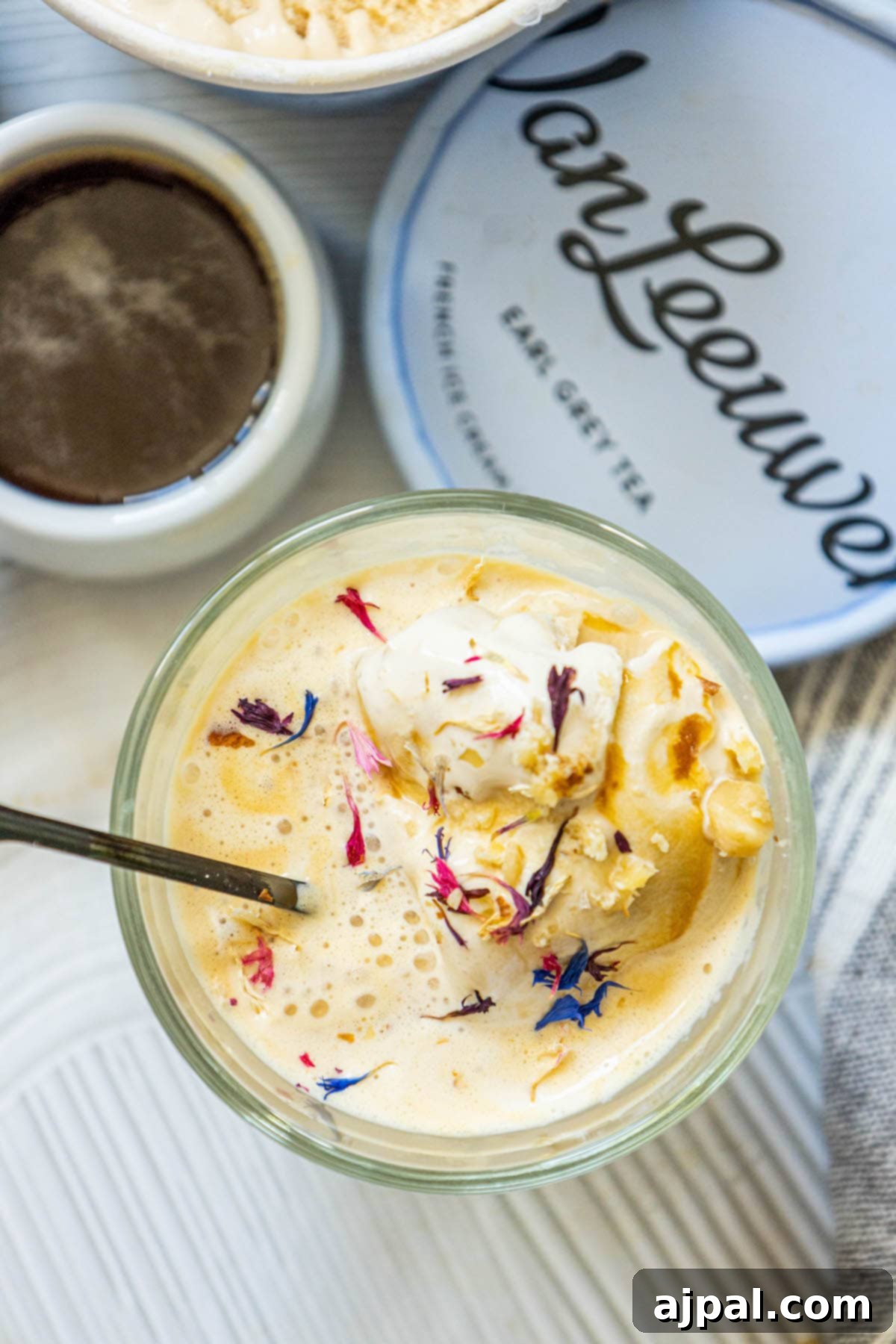 A close-up of a delightful Earl Grey Affogato served in a clear glass mug, topped with delicate edible cornflowers.