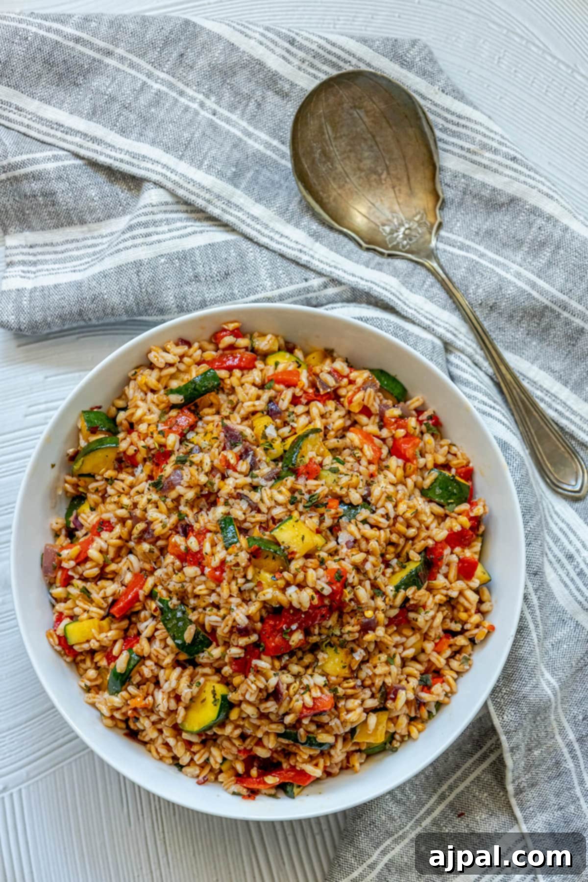 Vibrant Farro Salad with Zucchini and Bell Pepper 9 Farro salad with red pepper and zucchini in a white bowl, served with a spoon.