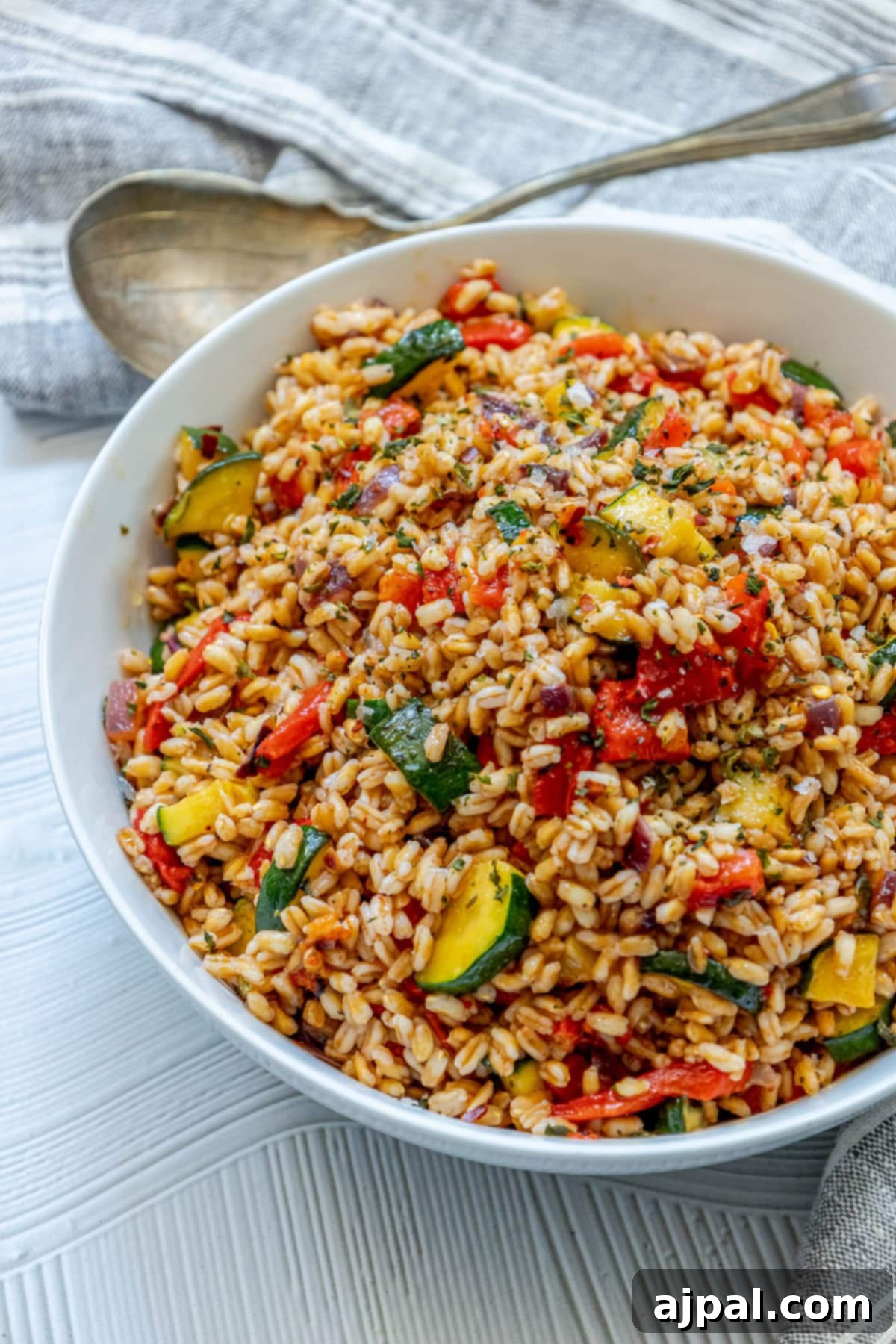 Vibrant Farro Salad with Zucchini and Bell Pepper 8 A bowl of roasted farro with a medley of colorful vegetables, including red pepper and zucchini, ready to be served.