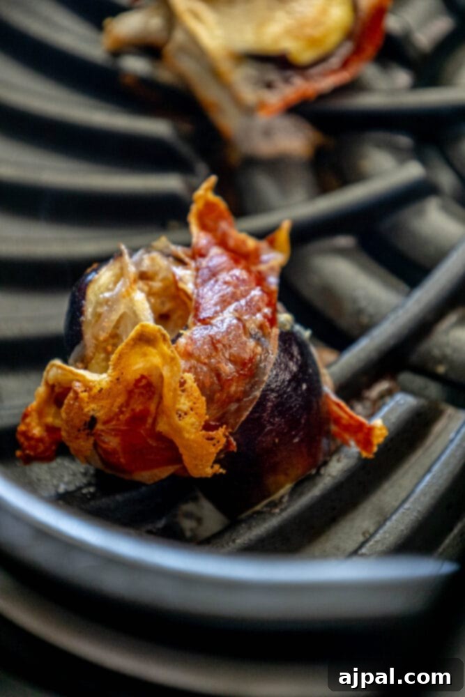 Gourmet Fig, Prosciutto, and Brie Bites 8 Picture of stuffed figs with brie wrapped in prosciutto, cooking on a grill or baking sheet