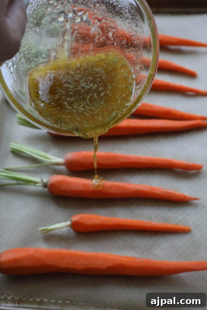 picture of hand pouring honey garlic sauce over carrots on parchment paper