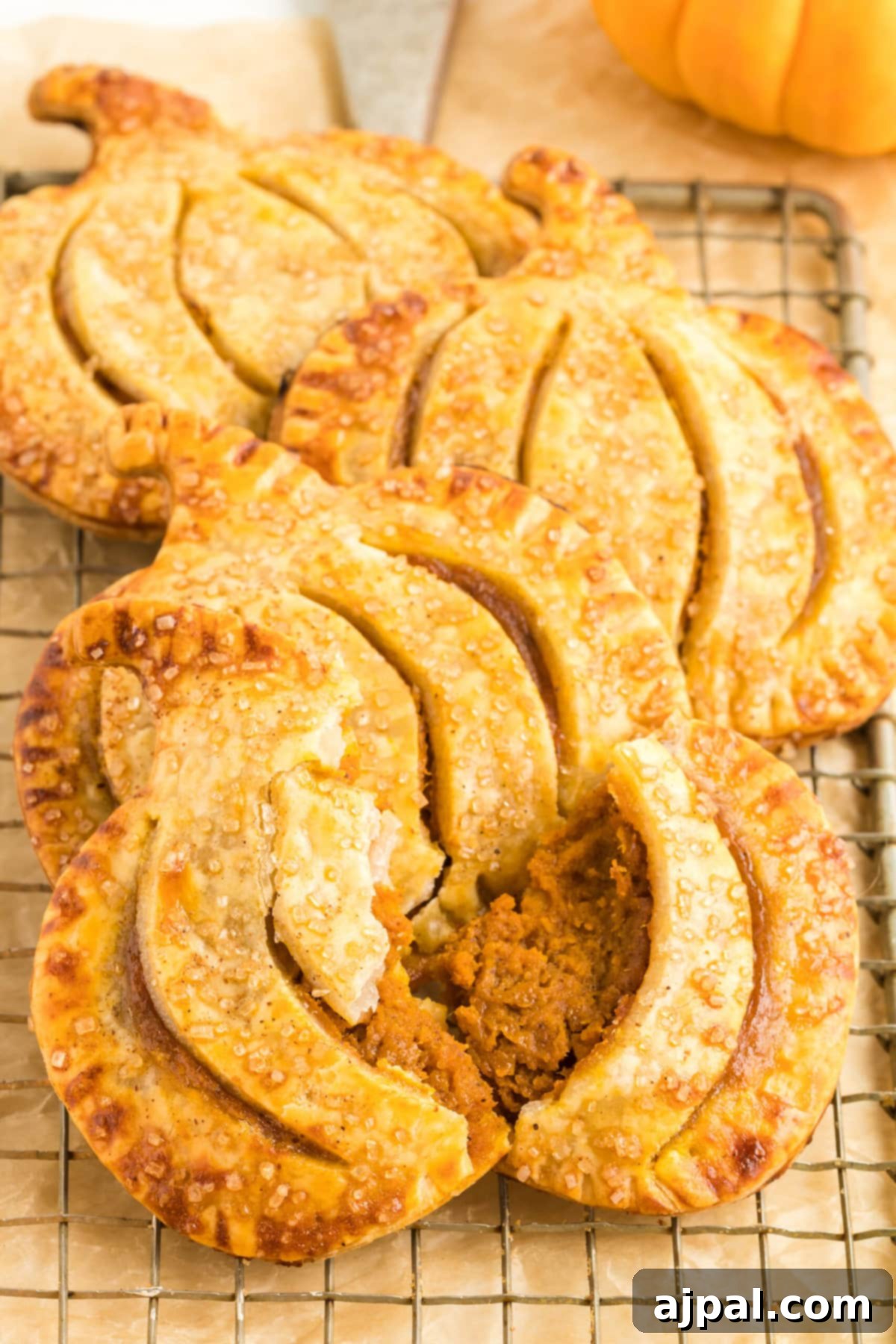 Autumn Pumpkin Pockets 4 A collection of perfectly baked pumpkin hand pies, golden and inviting, arranged on a cooling rack.