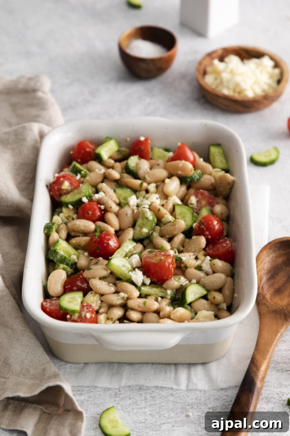 A delightful Mediterranean white bean salad with fresh tomatoes and cucumbers in a simple white bowl, highlighting its ease of preparation and vibrant freshness.