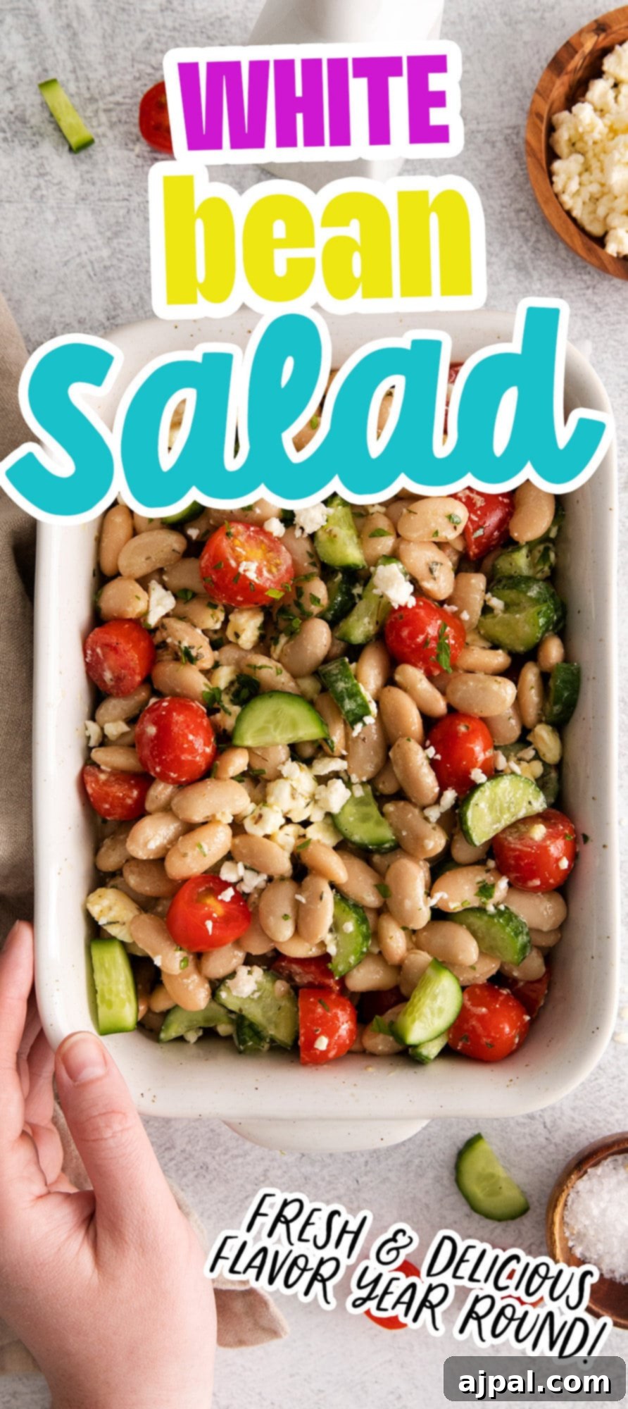 white bean salad in a white bowl with cucumber, tomatoes, and crumbled cheese