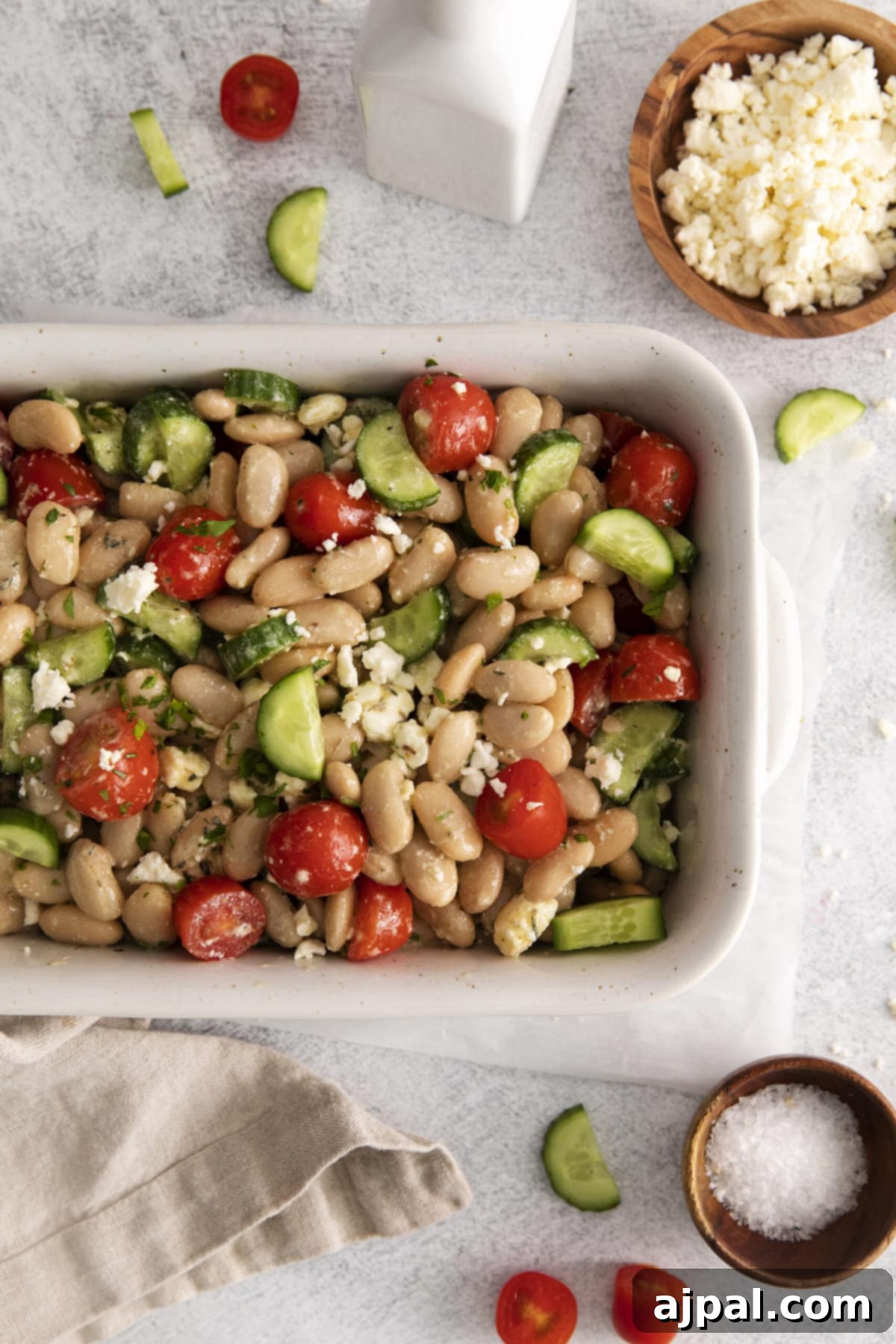 A vibrant Mediterranean white bean salad featuring fresh tomatoes, crisp cucumbers, and creamy feta cheese, perfectly dressed and ready to serve in a white bowl.