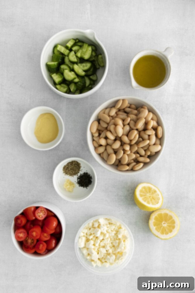 Various salad ingredients like beans, cucumber, herbs, spices, lemons, cheese, tomatoes, and olive oil arranged in separate bowls on a rustic wooden table.