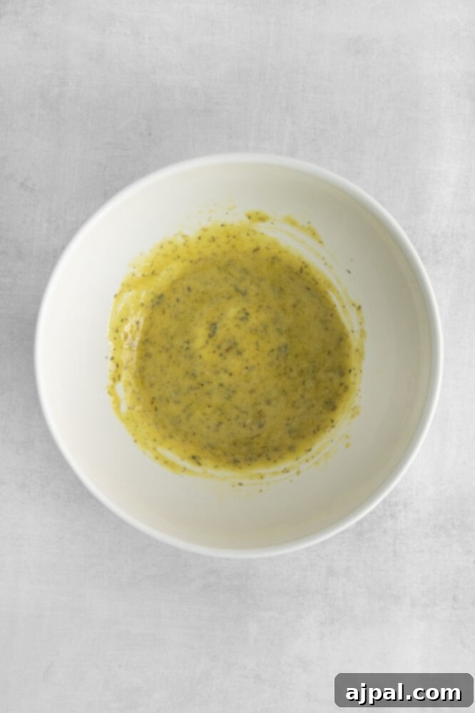 A smooth, golden salad dressing expertly emulsified and mixed in a glass bowl.