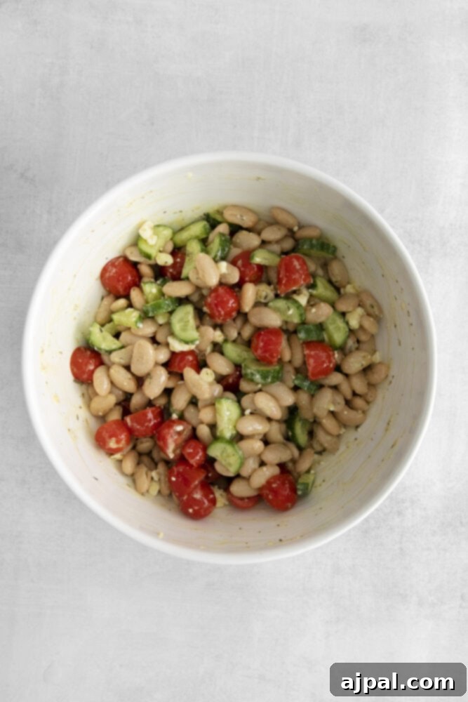 A freshly tossed white bean salad in a pristine white bowl, ready to be served.