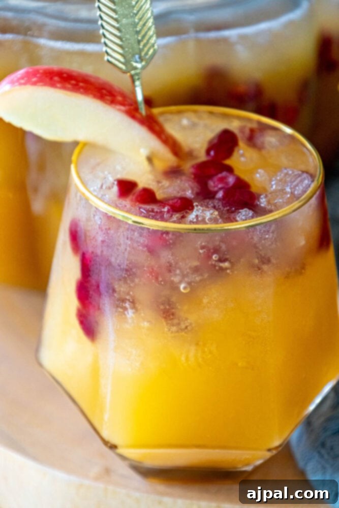 A glass of festive pumpkin punch with a slice of apple garnish, ready for an autumn party.