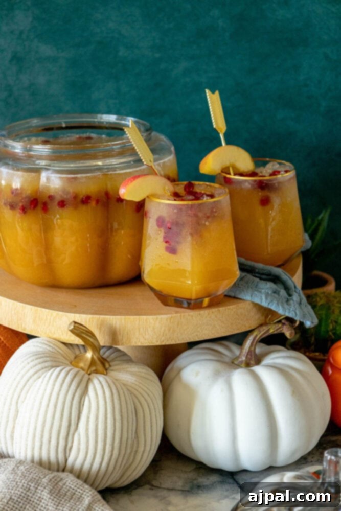 A glass of pumpkin punch on a table adorned with miniature pumpkins and autumn decor, perfect for fall entertaining.