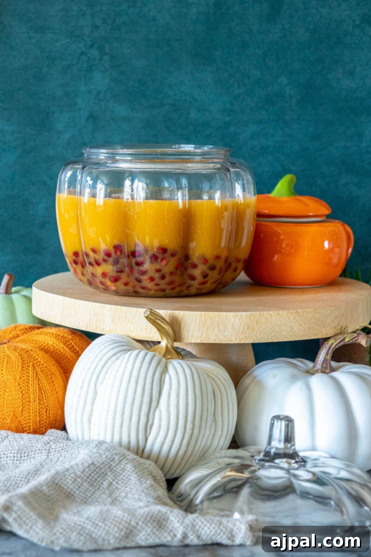 A large punchbowl filled with the combined pumpkin puree, apple cider, orange juice, and floating pomegranate seeds, chilling.