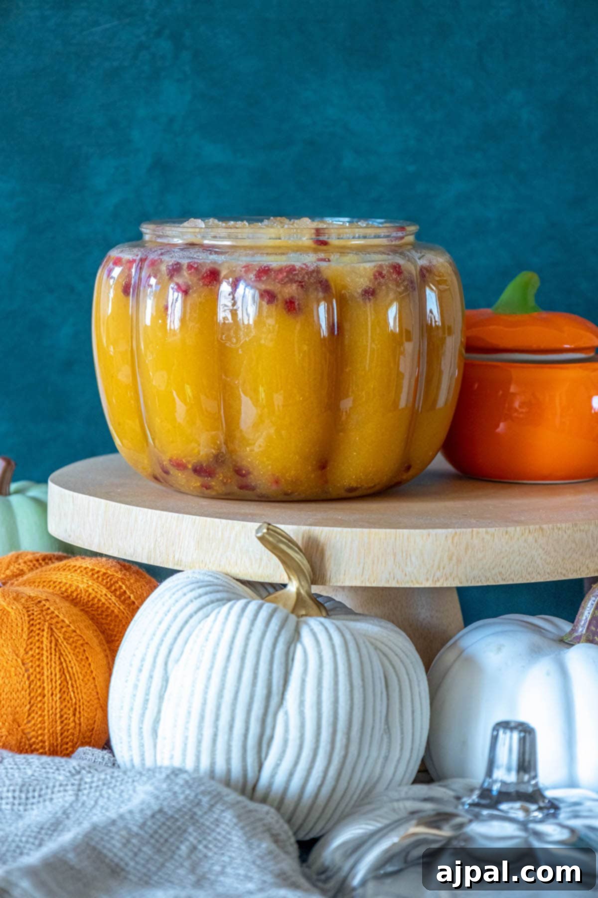 A festive jar of pumpkin pie punch with a decorative label, sitting on a wooden stand, ready for serving guests.