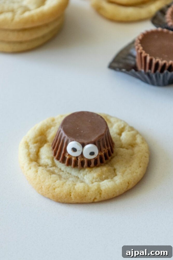 Spooky Spider Cookies 7 Candy eyes being carefully attached to a Reese's Peanut Butter Cup on a cookie using melted chocolate.
