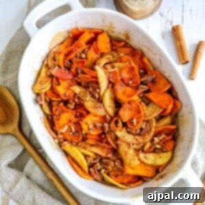 picture of baked cinnamon apples and sweet potatoes in a white baking dish with a spoon on a table