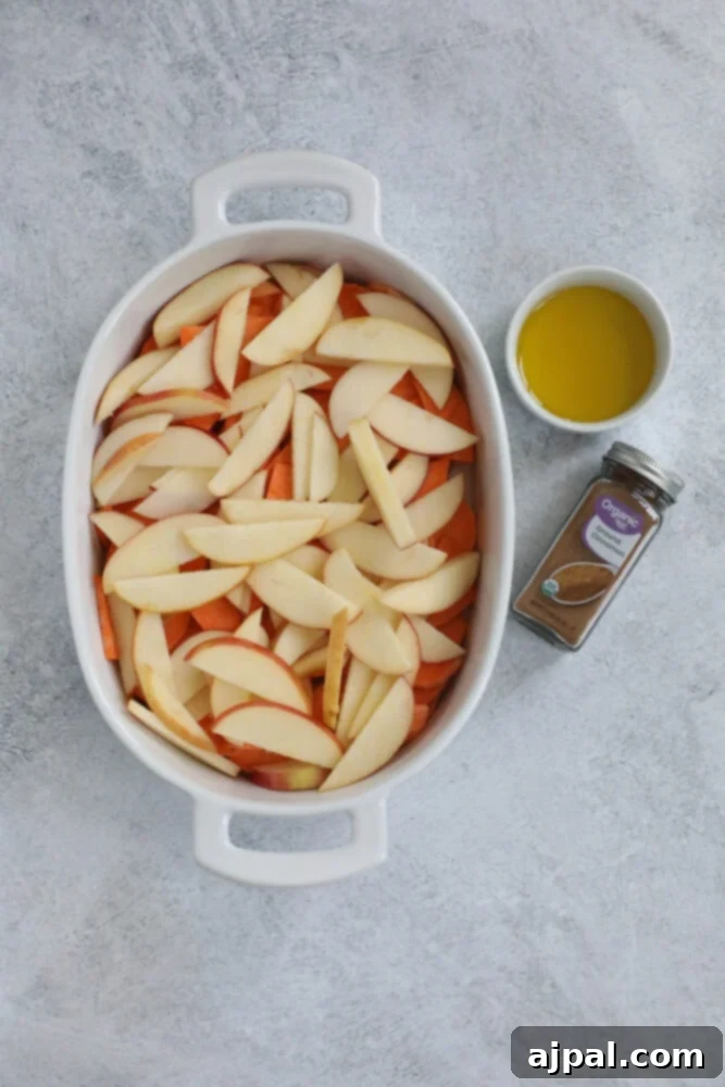 Layered slices of apples over sweet potatoes in a baking dish, creating a colorful foundation.