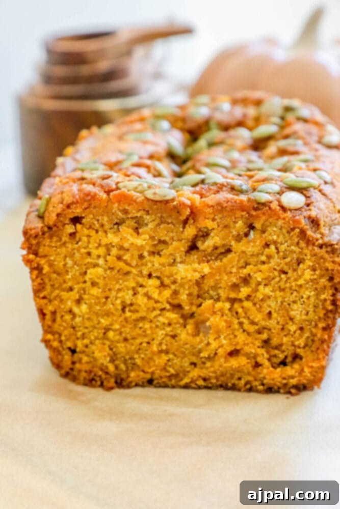 Starbucks-Inspired Pumpkin Bread 2 A slice of pumpkin bread with pumpkin seeds on a baking sheet.