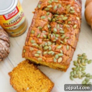 picture of pumpkin bread with pumpkin seeds baked onto the top sliced on a table