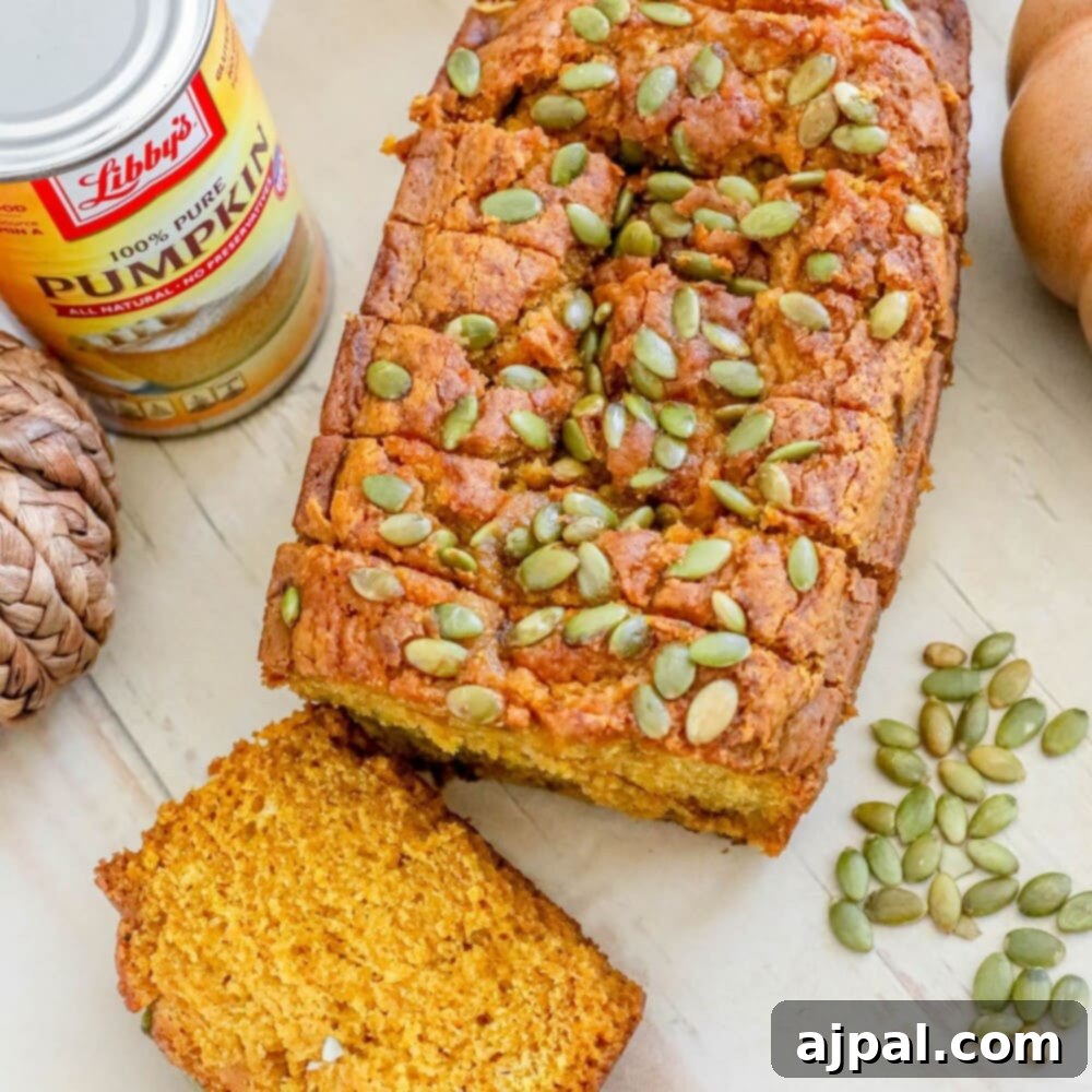 Starbucks-Inspired Pumpkin Bread 3 picture of pumpkin bread with pumpkin seeds baked onto the top sliced on a table