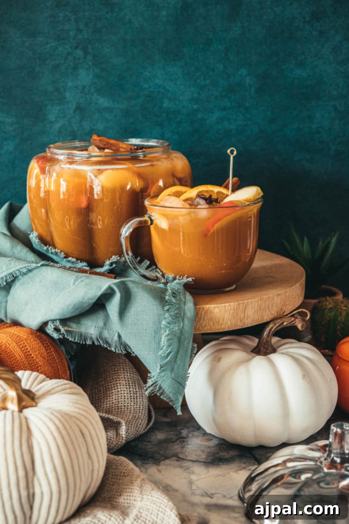 A festive autumn table featuring a glass of sparkling pumpkin punch, surrounded by decorative pumpkins, creating a warm and inviting atmosphere.