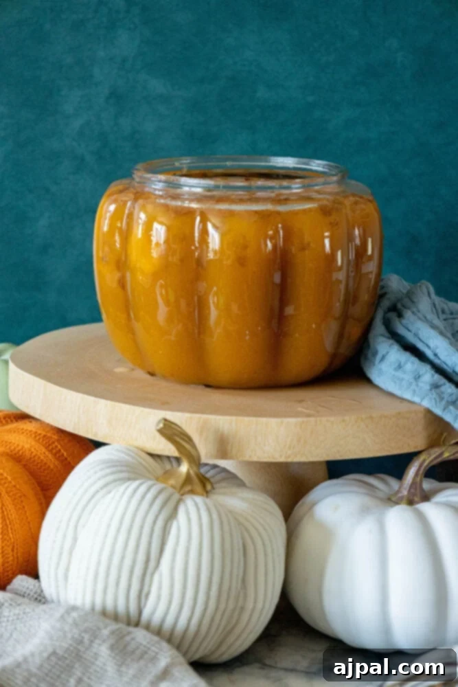 A rustic display featuring a jar of homemade pumpkin butter, prominently placed on a wooden stand, highlighting fresh fall ingredients.