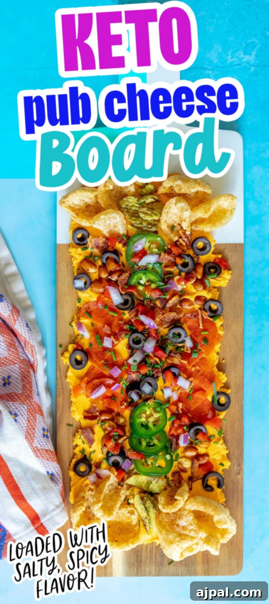 picture of pub cheese spread on a board covered with pork rinds, jalapenos, olives, bacon crumbles, peanuts, pimiento peppers, chives, red onion, and pepperoni