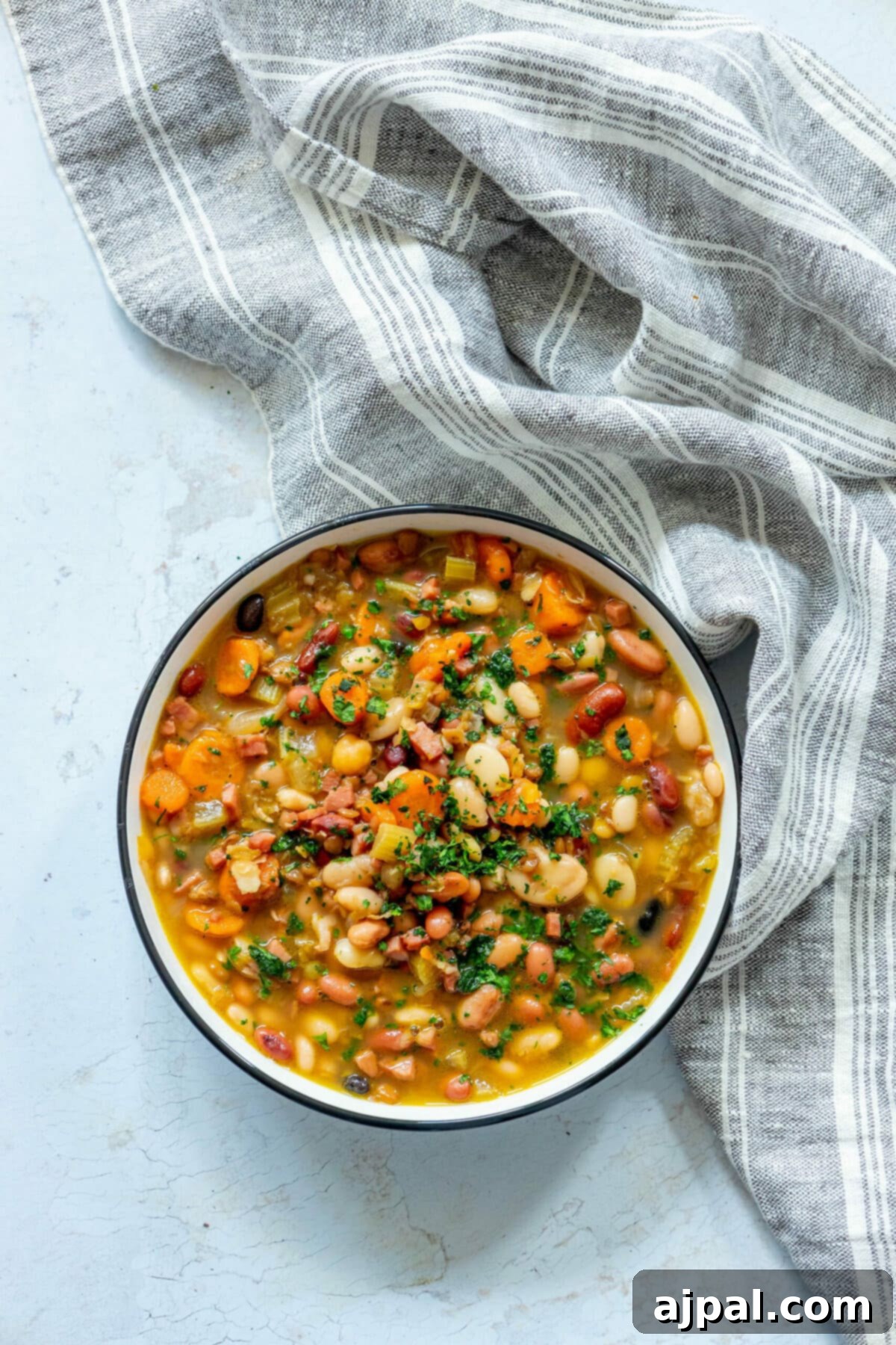 Smoked Ham and Bean Stew 11 picture of soup in a bowl with ham, beans, celery, and parsley on top