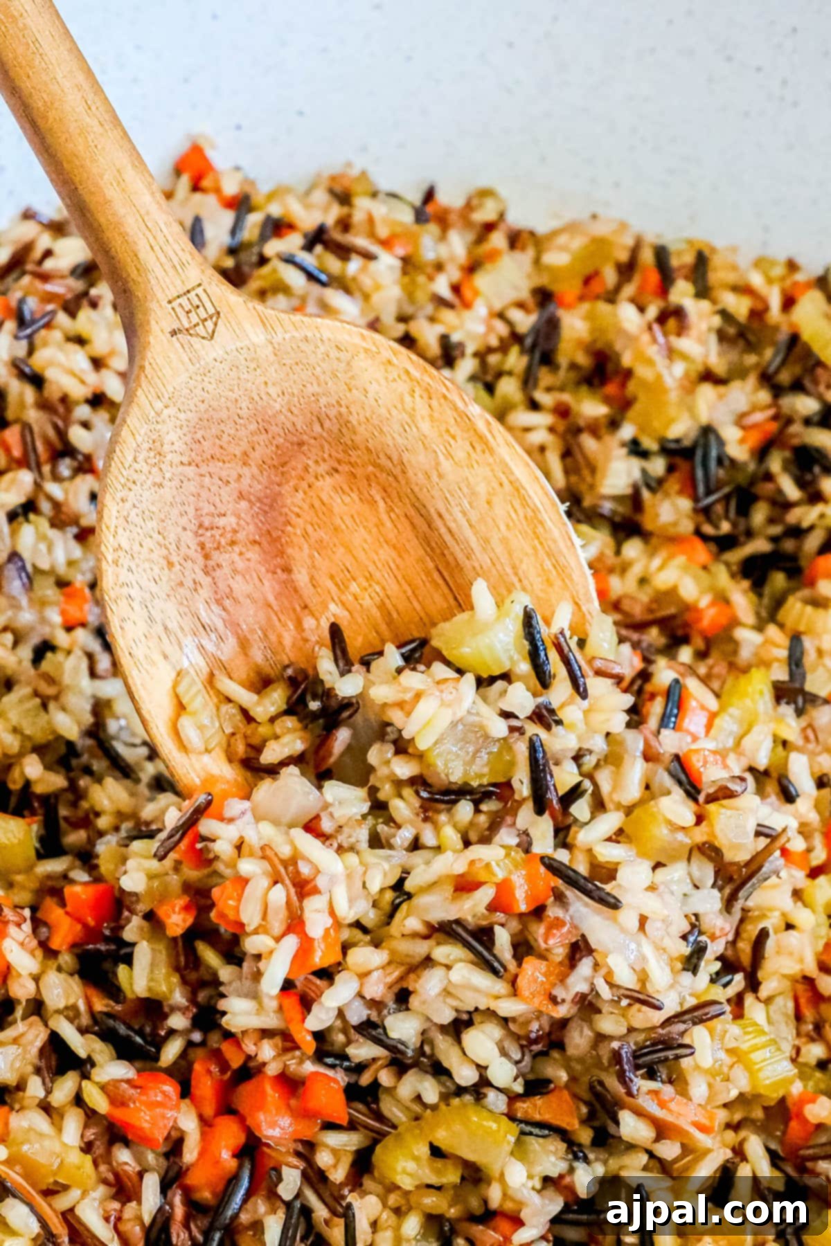 A wooden spoon delicately scooping fluffy, perfectly cooked wild rice pilaf from a white ceramic bowl, showcasing the rich texture and vibrant colors of the grains and vegetables.