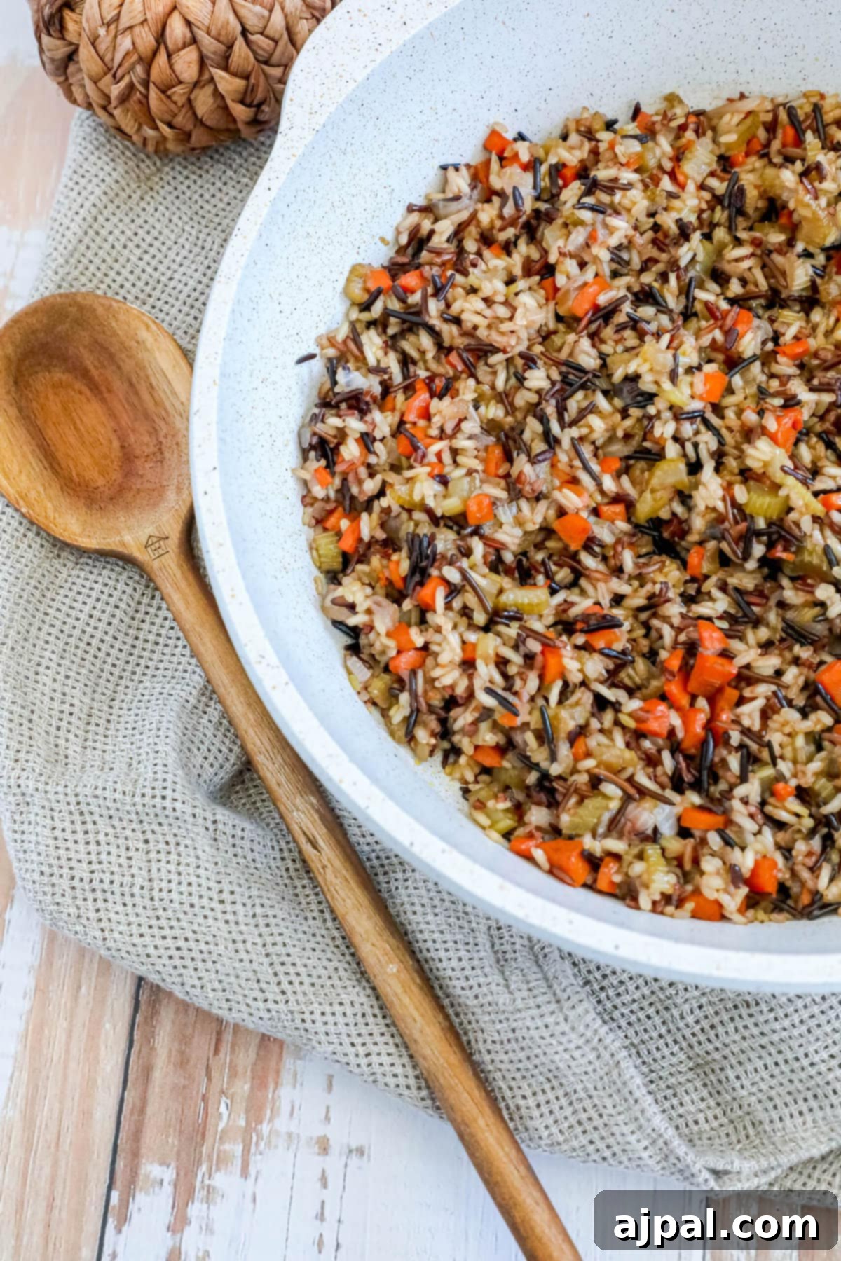 A close-up shot of hearty wild rice pilaf, glistening with oil and flecked with bright orange carrots, showcasing the rustic appeal and wholesome ingredients of the dish.